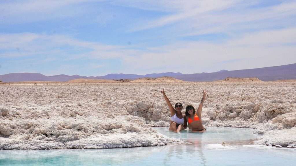 Disfrutando de un tour al salar de pedernales en la región de Atacama. Nadando en laguna turquesa con el volcán doña ines de fondo